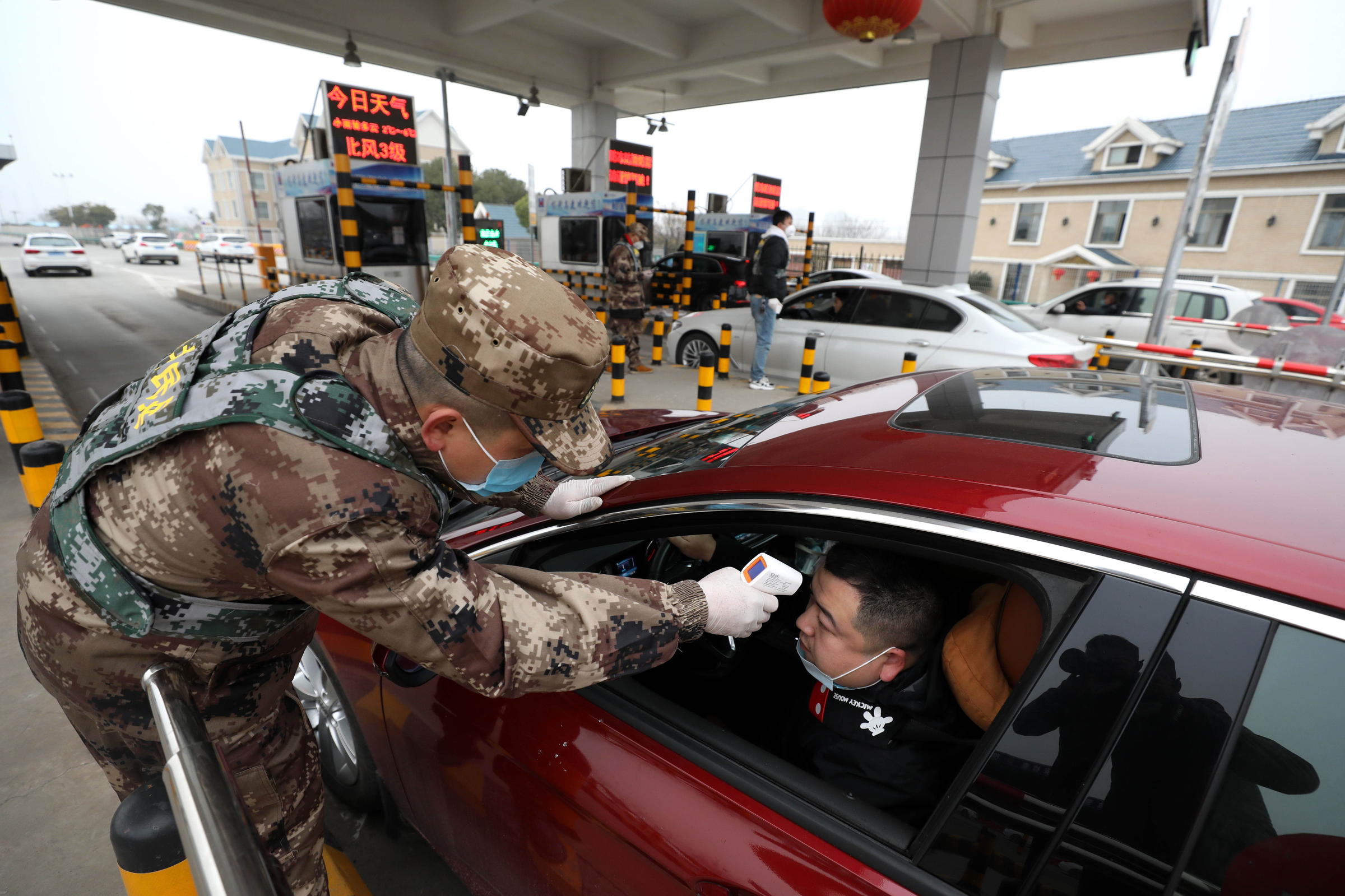 Seorang Petugas memeriksa suhu tubuh pengendara mobil terkait adanya virus Corona yang meluas di Wuhan, China